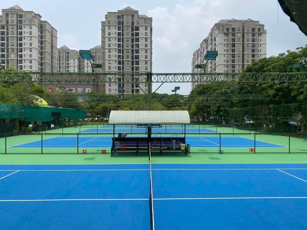 Toàn cảnh sân tennis với chung cư phía sau