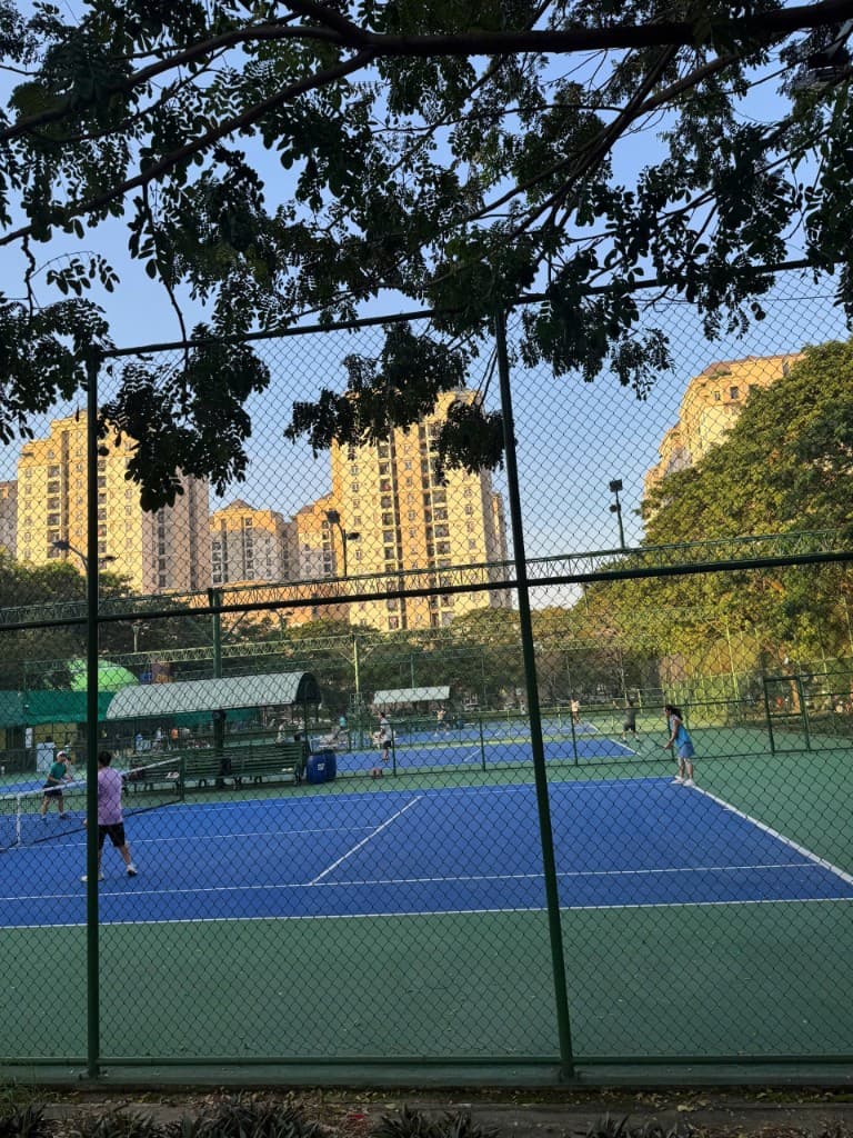 Sân tennis nhìn qua hàng rào xanh